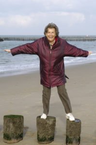 Senior balancing on logs at beach