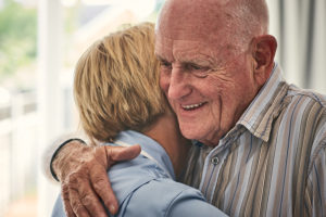 Home carer hugging senior male patient