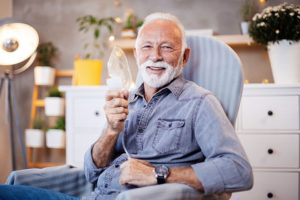 Man in chair smiles while holding oxygen mask showing that communicating about your COPD diagnosis can be easy.