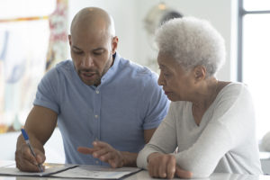 An elderly woman whose adult children knew the importance of designating a guardian for a senior parent works with a legal advisor on paperwork.