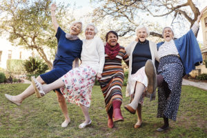 Five elderly women who have learned how to find friends as a senior lock arms and dance together.