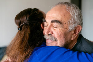 A woman who is one of many Alzheimer’s caregivers who care for a loved one alone hugs her aging father.