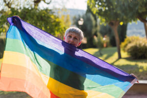 One of the older adults in the LGBTQ+ community proudly displays a rainbow flag.