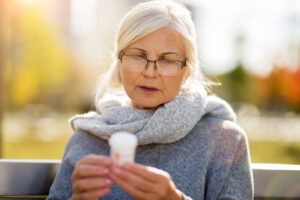 A woman who wants to prevent overmedication and adverse medication reactions in seniors studies a prescription pill bottle carefully.