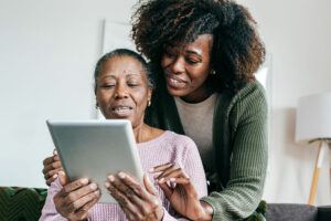 A woman shows her elderly mother how to use senior technology.