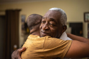 An older man receives a hug to calm him following catastrophic reactions in Alzheimer’s.