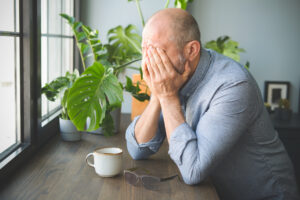 A man looks stressed and worried, which may be an indicator of PTSD in a senior loved one.