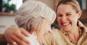 A woman who cares about emotional health in seniors shares her time and laughter with an older woman.