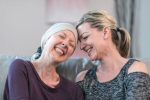 A woman talking to a loved one with cancer shares laughter and a hug.